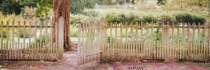 White wooden fence with an open gate in a garden setting